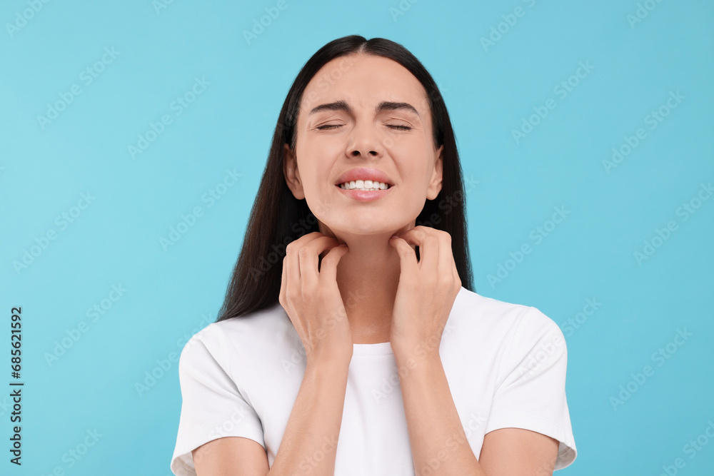 Suffering from allergy. Young woman scratching her neck on light blue background