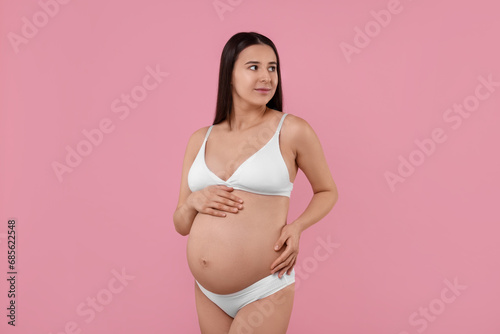 Beautiful pregnant woman in stylish comfortable underwear on pink background