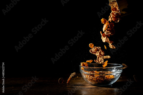 Corn flakes sprinkle on a bowl on black background
