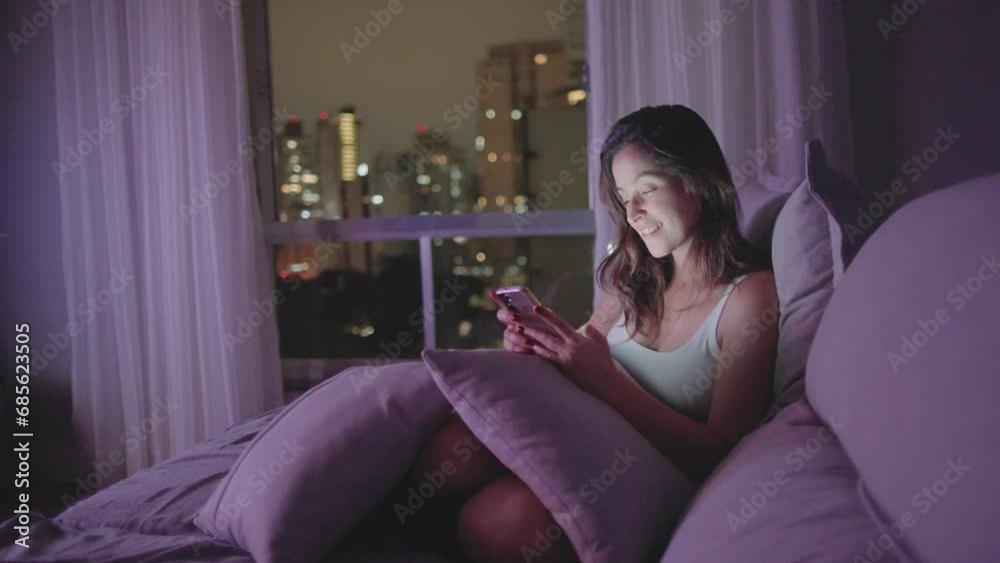 A relaxed woman using smartphone device at home living room couch at night. Closeup woman staring at phone at night
