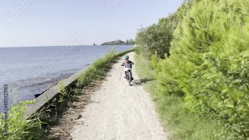 Young child biking along the coast of the Mediterranean Sea near Grado, Italy
