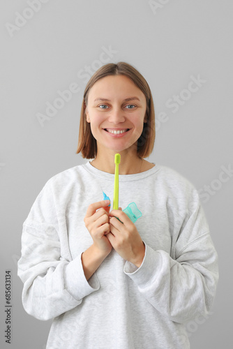 Health care dentistry and oral hygiene concept. Smiling young woman holds dental floss, toothbrush and interdental brush to for prevent oral disease. Daily routines caries prevention
