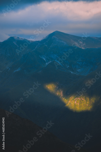 The ray of light hitting the side of a rocky mountain. Cloudy weather after a summer storm in the Carpathian Mountains of Romania