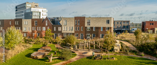 Panorama of inclusive neighbourhood park sunlit in the foreground and row of contemporary homes photo