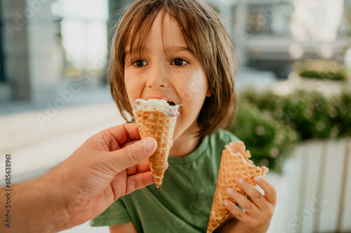 Father's hand feeding ice cream to son photo