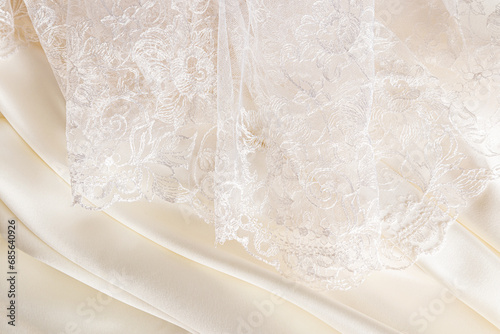 part of a beautiful beige lace tulle fabric or part of a bride's wedding dress on a beige satin background. space for text. Design layout.