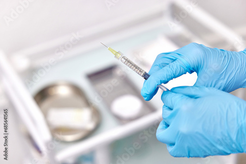 Physician hand in blue gloves with syringe for injection photo