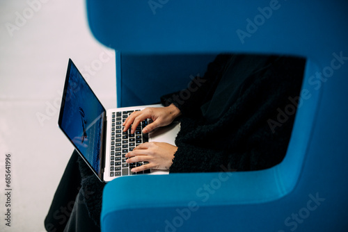 Businesswoman typing on laptop keyboard sitting in office
