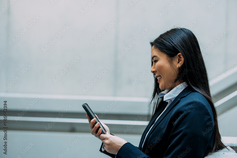 Smiling businesswoman using smart phone at workplace Smiling businesswoman using smart phone at workplace