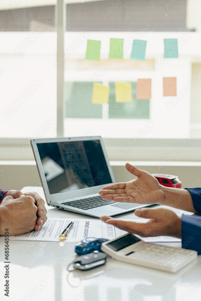 Fototapeta premium A car dealer with a customer, the new owner, signs a lease-purchase document. car sales contract The employee explains the installment payment terms. vertical picture