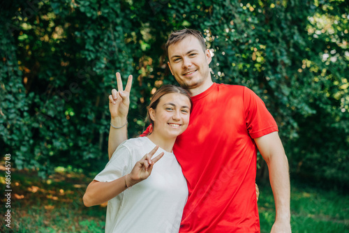 Smiling brother and sister showing peace sign in park