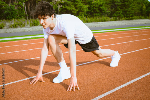 Teenage boy preparing for running race on track in stadium photo