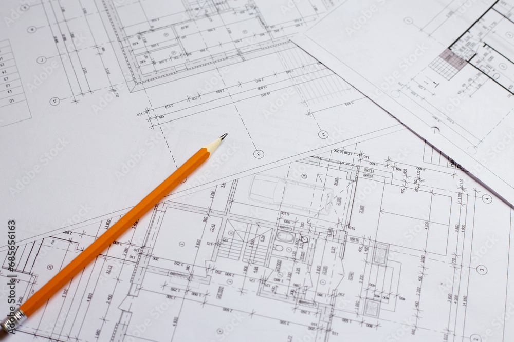 pencil and office tools for writing on the blueprint of construction industry. Place the rolls on a desk over blurred blueprint for construction industry background. pencil and office tools for writing on the blueprint of construction industry. Place the rolls on a desk over blurred blueprint for construction industry background.