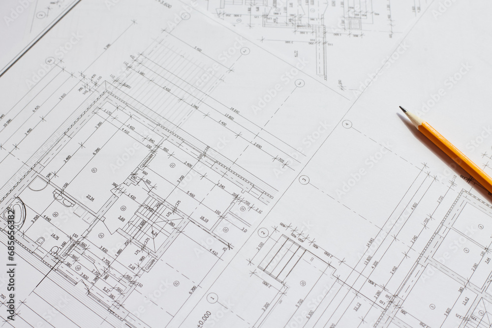 pencil and office tools for writing on the blueprint of construction industry. Place the rolls on a desk over blurred blueprint for construction industry background. pencil and office tools for writing on the blueprint of construction industry. Place the rolls on a desk over blurred blueprint for construction industry background.