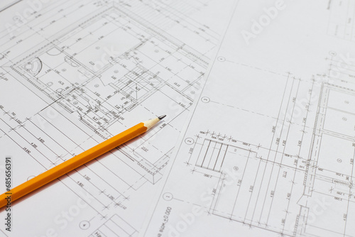 pencil and office tools for writing on the blueprint of construction industry. Place the rolls on a desk over blurred blueprint for construction industry background.