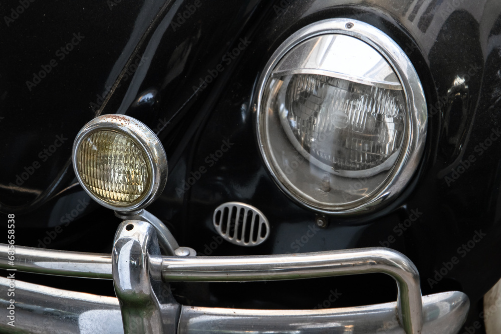 Round headlights of a vintage black car. Close-up