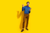 Full size photo of handsome guy dressed striped shirt indicating at sale empty space hold smartphone isolated on yellow color background