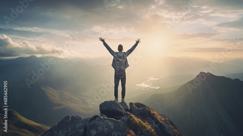 Positive man celebrating on mountain top with arms