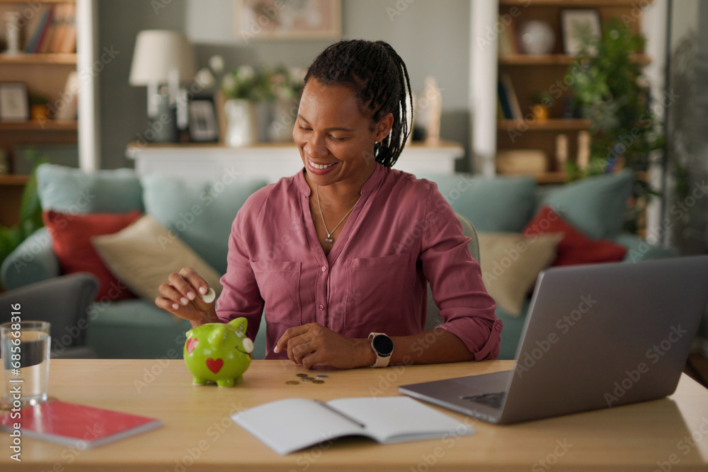 Happy woman putting coins in piggy bank- money saving concept