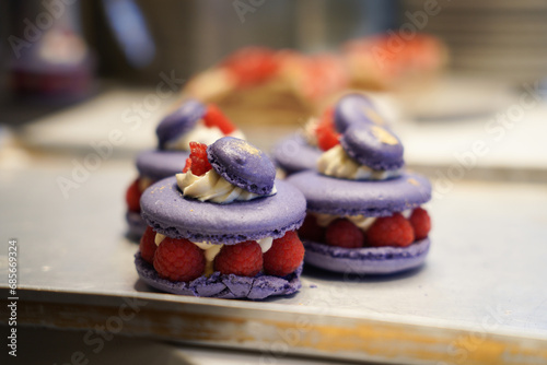 Close up of purple macaron filled with cream and raspberry.