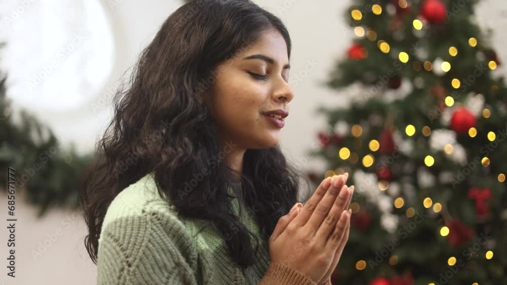 Portrait of charming happy indian woman making a wish asking for blessing and help before holidays near Christmas tree at cozy home Winter holidays mood Portrait of charming happy indian woman making a wish asking for blessing and help before holidays near Christmas tree at cozy home Winter holidays mood