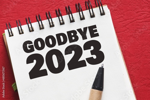 GOODBYE 2023 text in an office notebook on a red table. photo