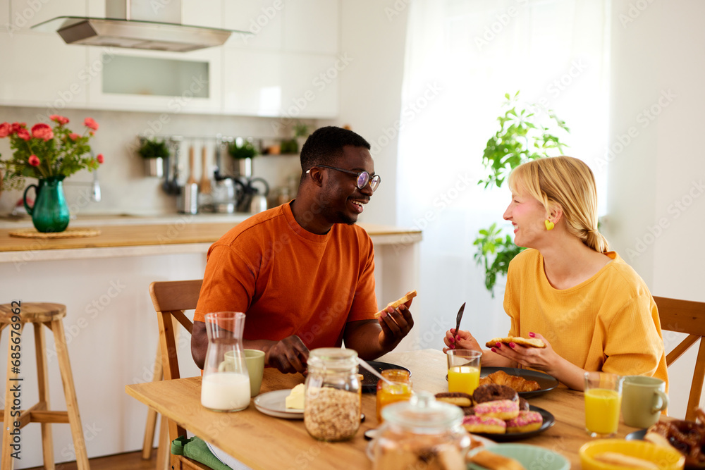 Multiracial couple enjoying breakfast together at home Multiracial couple enjoying breakfast together at home