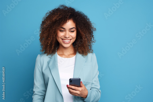 Portrait of a happy young african american woman using mobile phone on blue background