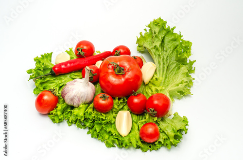 Mix of fresh vegetables - pepper,garlic, tomatoes and green salad leaves. White background, isolated..