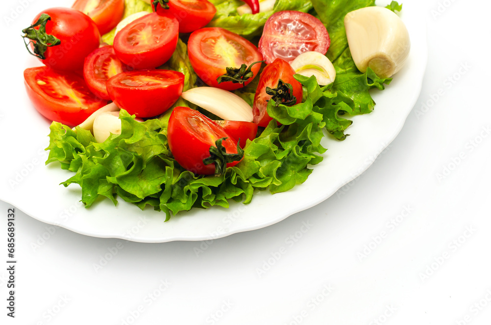 Delicious vegetable salad in a bowl on a white background. Chopped tomatoes, lettuce, garlic.