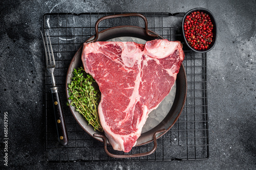 Fresh raw T-bone marbled beef meat Steak on a steel tray. Black background. Top view photo