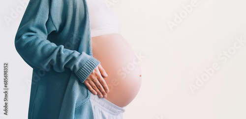 Pregnant woman holds hands on her belly. Pregnancy, maternity, preparation and expectation concept.