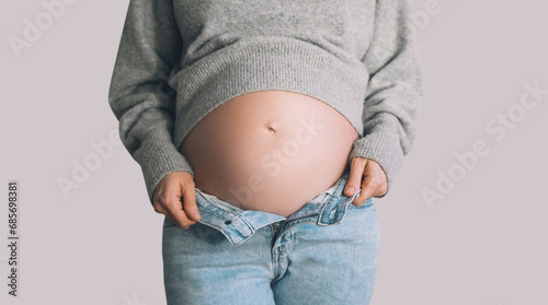 Pregnant woman belly in unzipped jeans. Pregnancy, maternity, preparation and expectation concept.