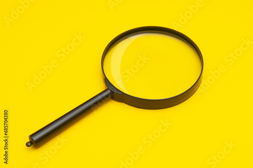 Magnifying lens close up on a yellow background