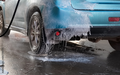 Manual car wash with pressurized water in car wash outside. Summer Car Washing. Cleaning Car Using High Pressure Water. Washing with soap. Close up concept.