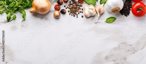 Cooking ingredients spices black pepper garlic onion with greens and tomatoes on a white stone table Copy space image Place for adding text or design