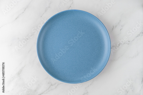 Empty vintage style blue plate on white marble table background. Cuisine mockup with copy space