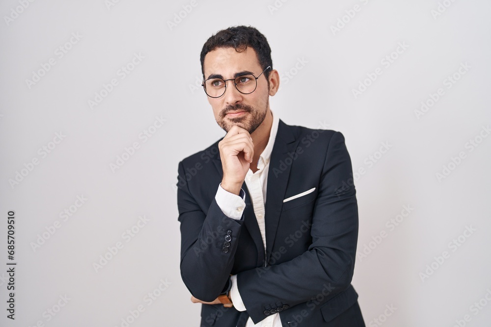 Handsome business hispanic man standing over white background looking confident at the camera smiling with crossed arms and hand raised on chin. thinking positive. Handsome business hispanic man standing over white background looking confident at the camera smiling with crossed arms and hand raised on chin. thinking positive.