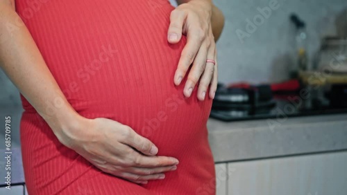 Wallpaper Mural A young pregnant girl with a large stomach, stands in the kitchen in a colorful dress and touches her stomach with her hands. Torontodigital.ca