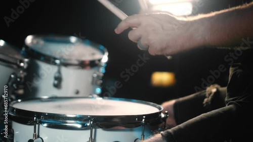 The drummer plays drums in a dark studio with lights on the back. photo