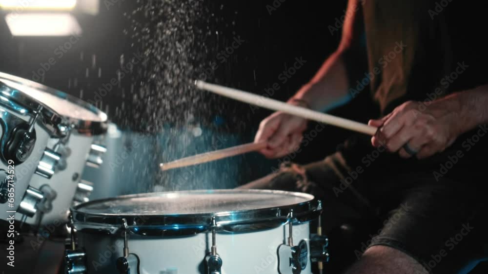 The drummer plays drums in a dark studio with lights on the back. The drummer plays drums in a dark studio with lights on the back.