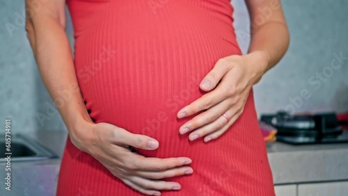 Wallpaper Mural A young pregnant girl with a large stomach, stands in the kitchen in a colorful dress and touches her stomach with her hands. Torontodigital.ca