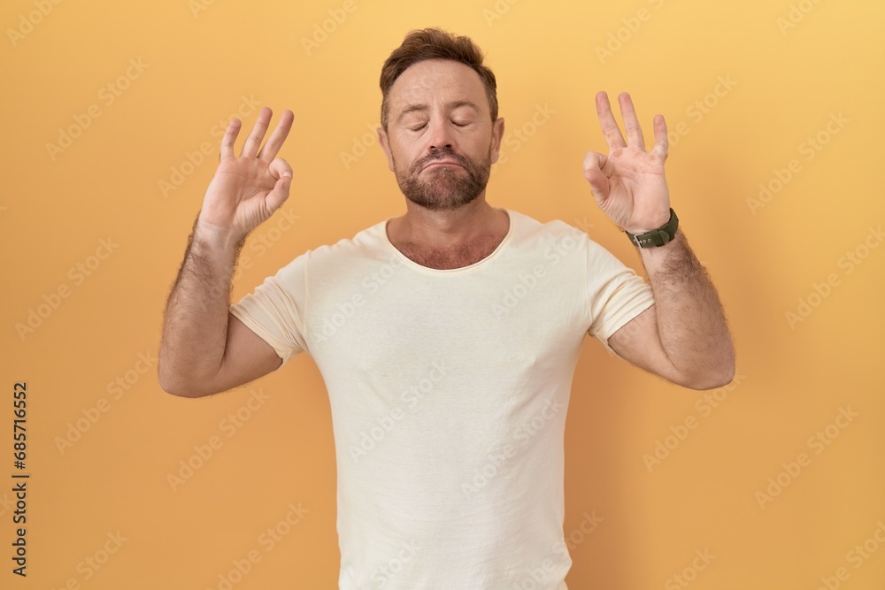Middle age man with beard standing over yellow background relaxed and smiling with eyes closed doing meditation gesture with fingers. yoga concept. Middle age man with beard standing over yellow background relaxed and smiling with eyes closed doing meditation gesture with fingers. yoga concept.