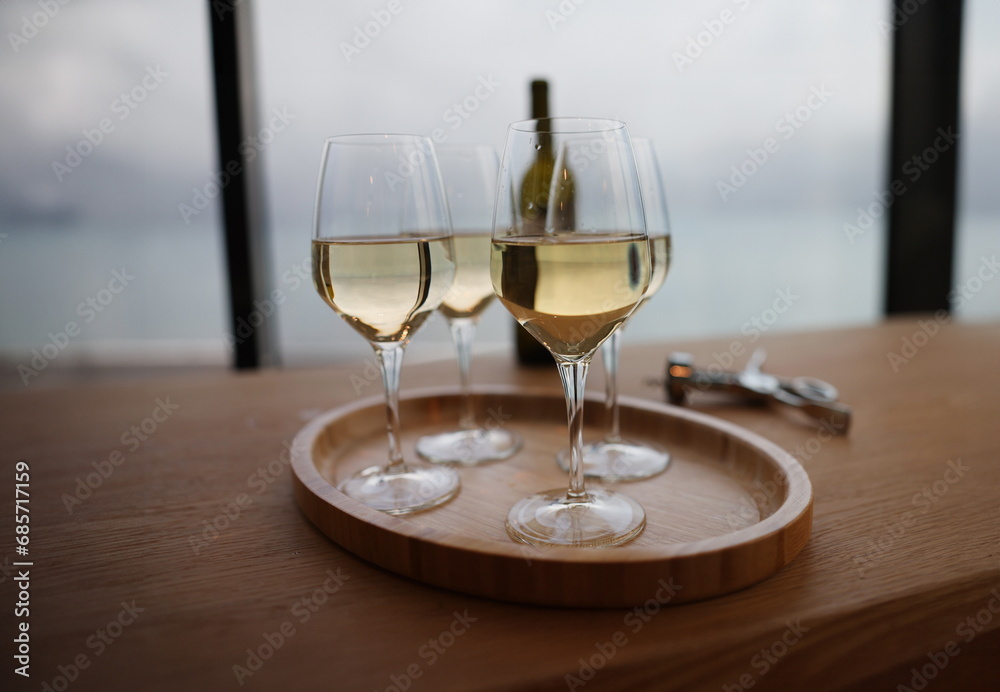 Lot of glasses with white wine and bottle standing on table in restaurant closeup. Celebration for birthday with alcohol concept