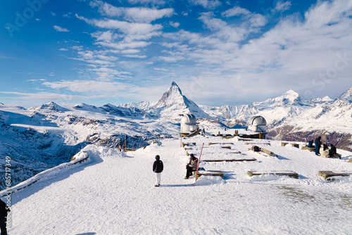 Tourists enjoying a panoramic view of the mighty Matterhorn, Switzerland on a cold sunny winter morning, from the peak of the Gornergrat.