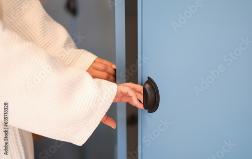 Women hands in bathrobe opening doors of blue wardrobe at home closeup. Clothes storage comfortable furniture and fittings concept