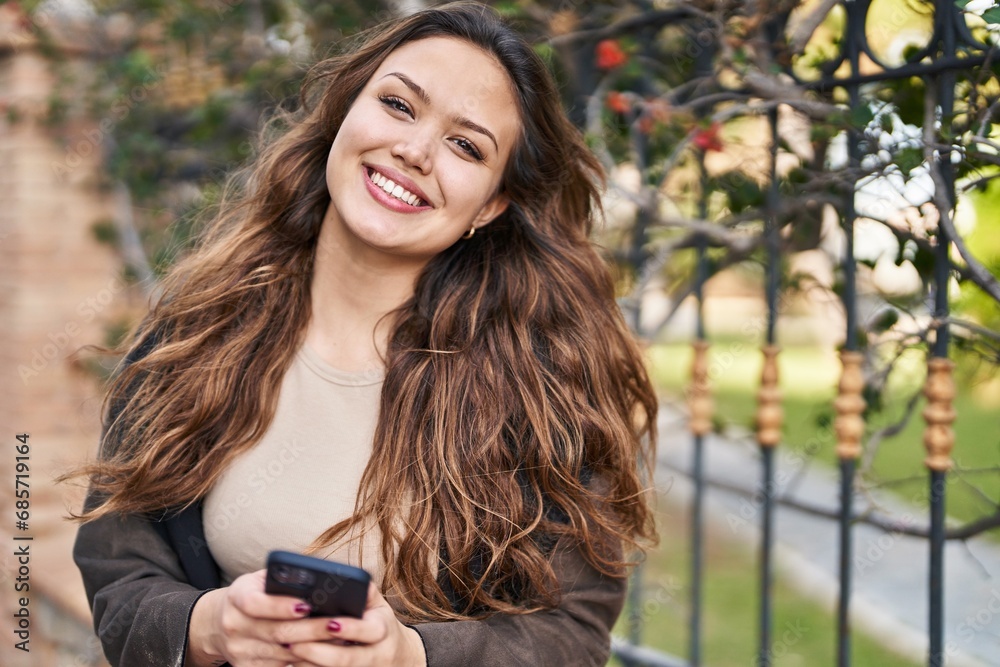 Young beautiful hispanic woman smiling confident using smartphone at park