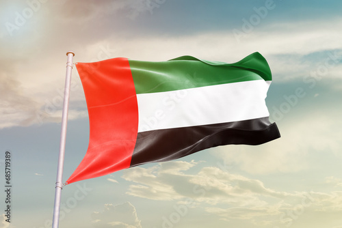 United Arab Emirates national flag waving in beautiful sky. The symbol of the state on wavy silk fabric.