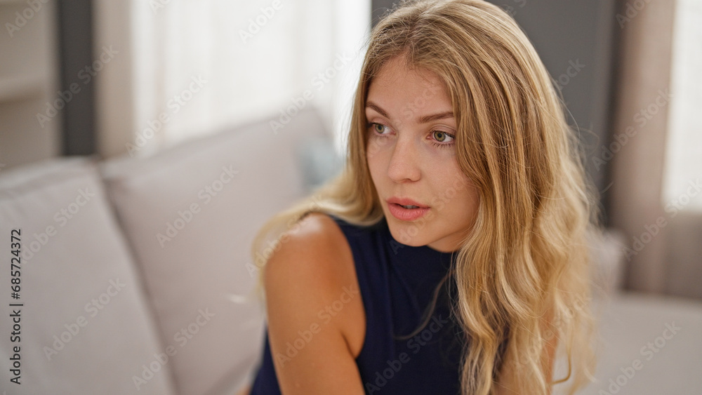 Young blonde woman sitting on sofa speaking at home Young blonde woman sitting on sofa speaking at home