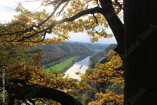 Autumn colors and view of a boat on the Elbe river from up the woods of the Elbe Sandstone Highlands national park in Saxony, Germany